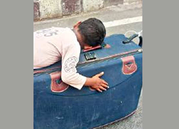 सूटकेस पर ही सो गया बच्चा